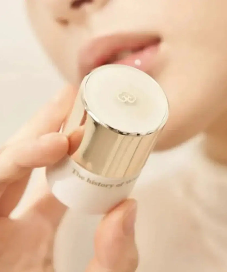 THE WHOO Royal Essential Golden Lip Serine 15ml held in hand near lips, showcasing luxurious lip care product.