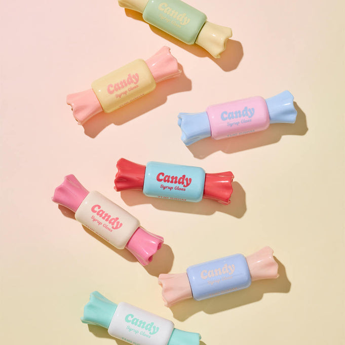 Colorful tubes of THE SAEM Saemmul Candy Syrup Gloss styled as candies, showcasing vibrant packaging on a pastel background.