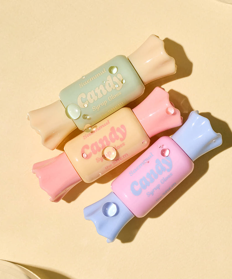Colorful packs of THE SAEM Saemmul Candy Syrup Gloss arranged on a beige background.