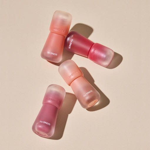 Assorted shades of THE SAEM Saemmy's Crema Velvet Tint arranged on a beige backdrop