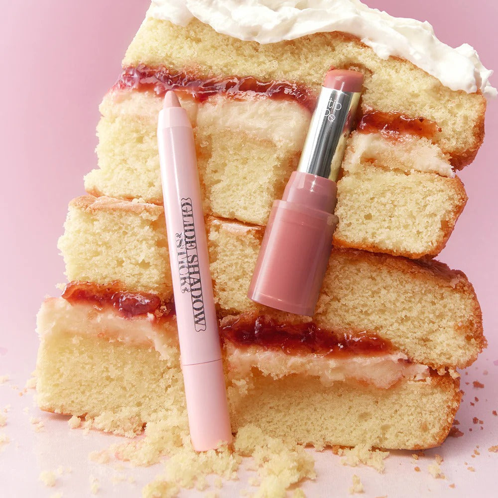 TIP TOE Glide Shadow Stick and lipstick on a slice of layered cake with icing