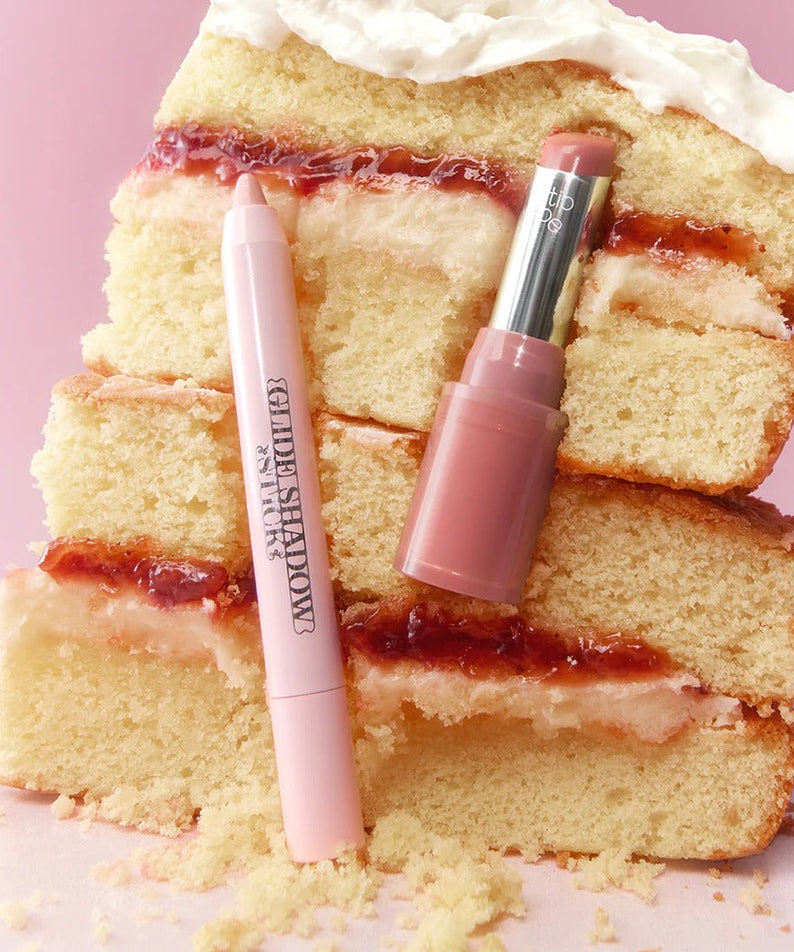 TIP TOE Glide Shadow Stick and lipstick on a slice of layered cake with icing