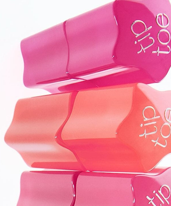 Stack of TIP TOE Glowit Sorbet Tint tubes in vibrant pink and peach shades for lip and cheek tinting