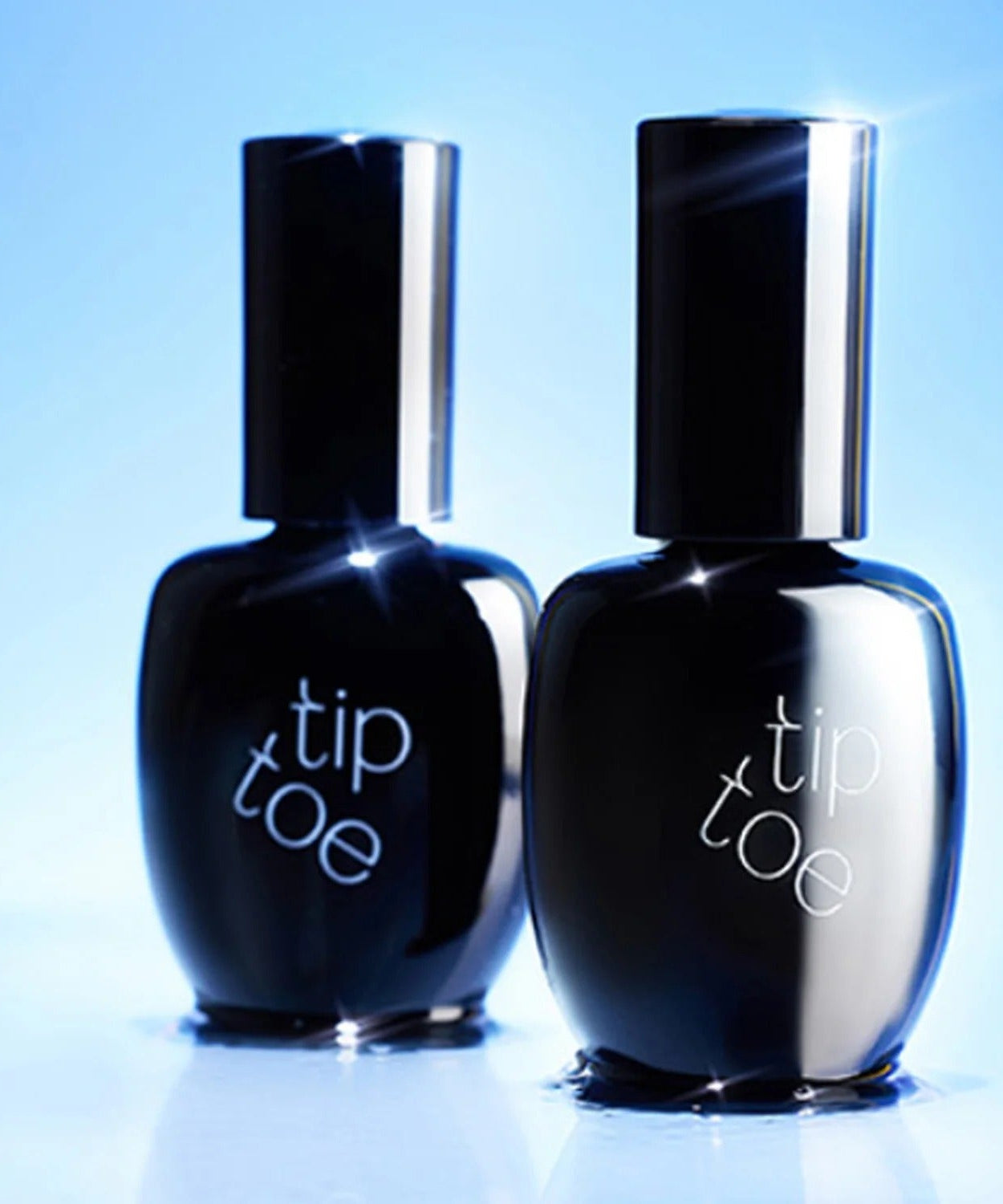 Two bottles of TIP TOE Sheer Topcoat Nail Polish on a reflective surface.