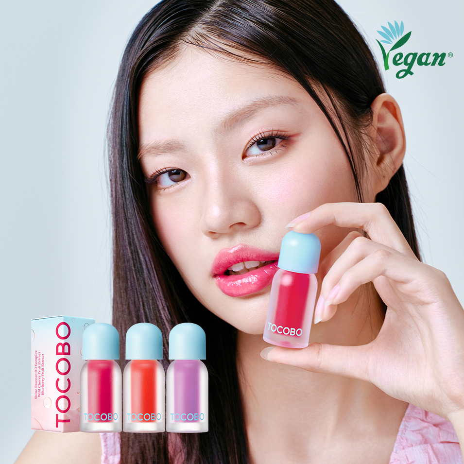 Model holding TOCOBO Juicy Berry Pluming Lip Oil next to lip oil bottles and vegan logo.