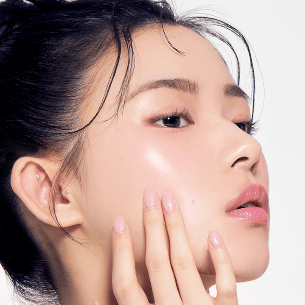 Close-up of a woman with glowing skin and elegant makeup, highlighting the effects of TONY MOLY Eyetone Strong Eye Lash Serum.
