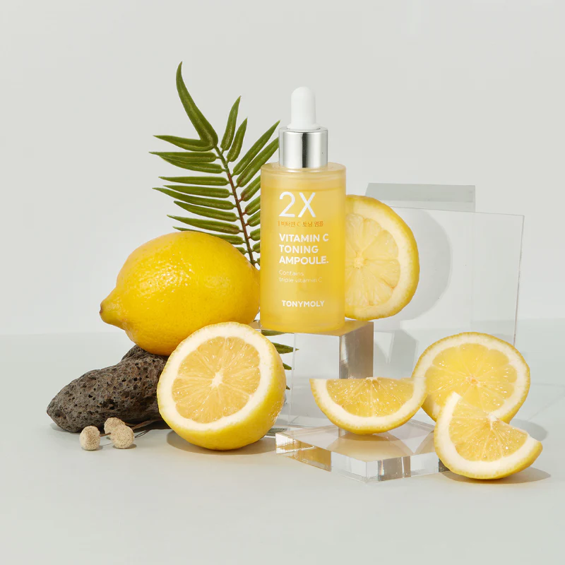 TONYMOLY 2X Vitamin C Toning Ampoule 50ml with fresh lemon slices displayed on a clear surface for vibrant skincare enhancement.