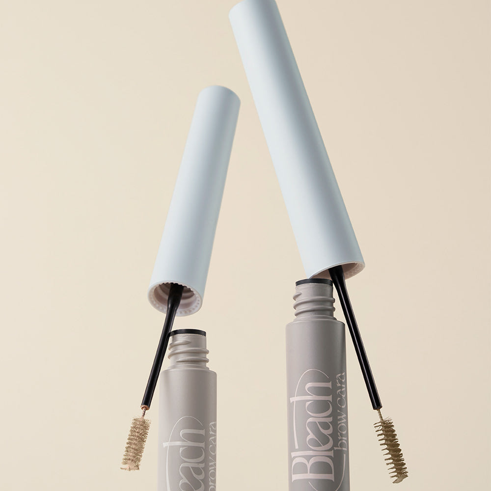 TOO COOL FOR SCHOOL Bleach Brow Cara, eyebrow mascara product image with open lids and brushes, beige background.