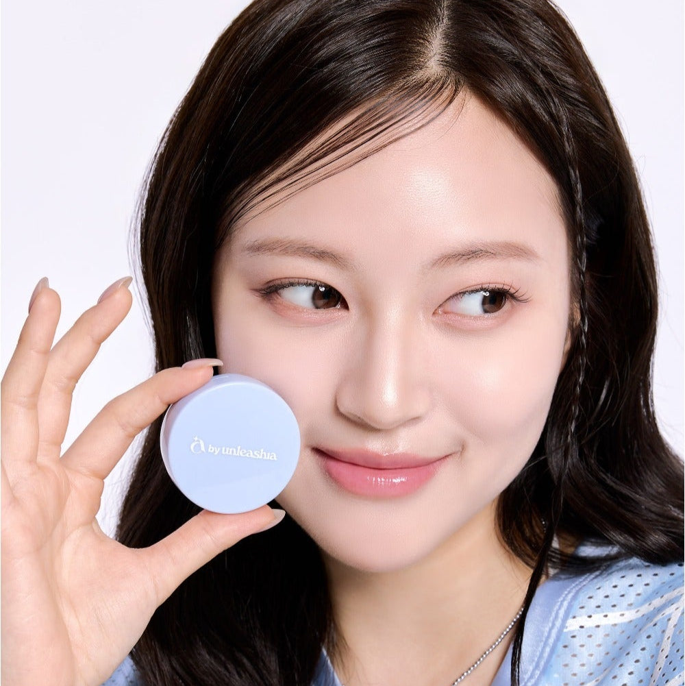 Woman holding UNLEASHIA Be Be Blue Cushion, showing vibrant packaging and radiant skin.