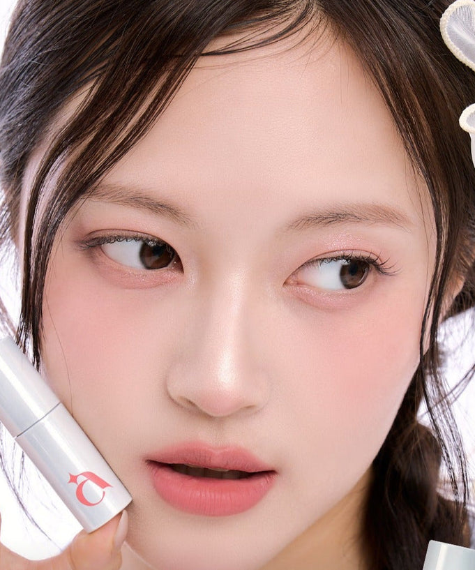 Model holding UNLEASHIA Clound Kiss Velvet Tint, showcasing its smooth application and natural finish lipstick.