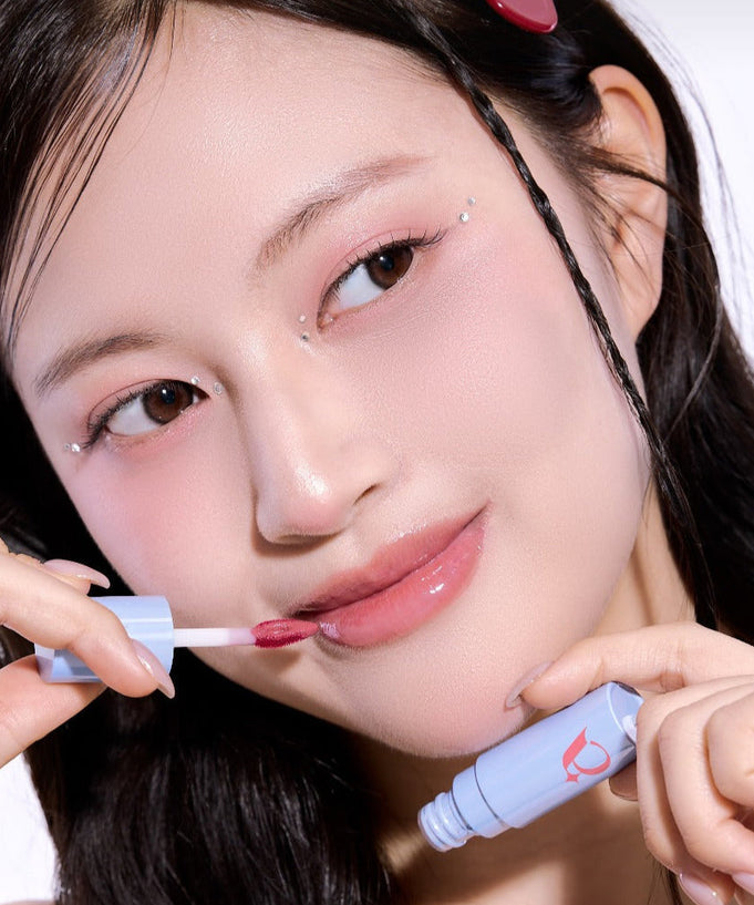 Woman applying UNLEASHIA Tanghulu Glaze Tint on lips for a glossy finish.