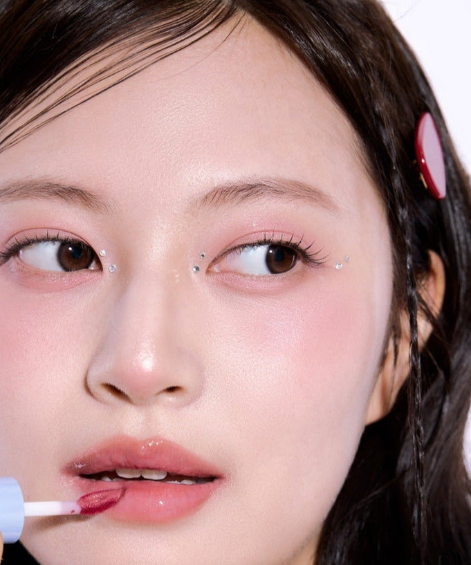 Woman applying lipstick with UNLEASHIA Tanghulu Glaze Tint, close-up shot showing glossy finish and vibrant color.
