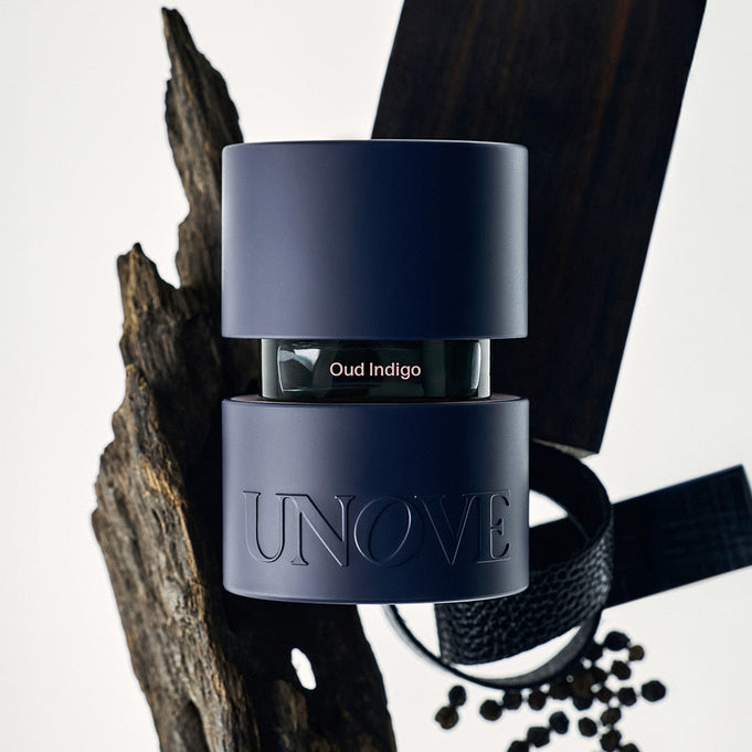 UNOVE Eau De Parfume bottle with modern design, surrounded by wood and spices, embodying the essence of luxury fragrance.