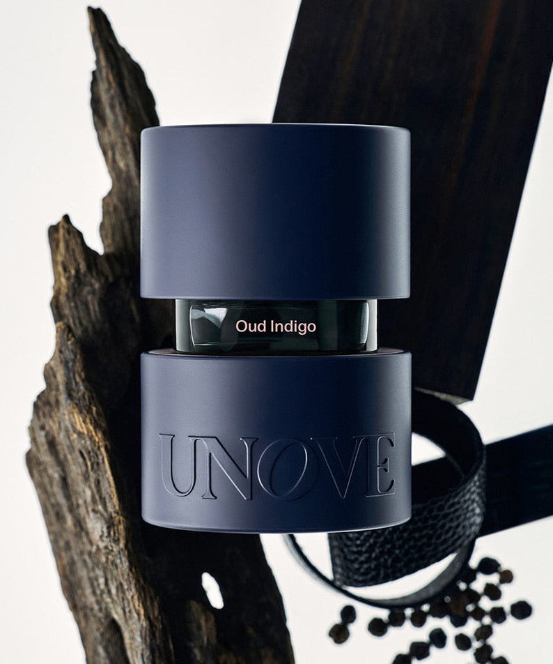 UNOVE Eau De Parfume bottle with modern design, surrounded by wood and spices, embodying the essence of luxury fragrance.