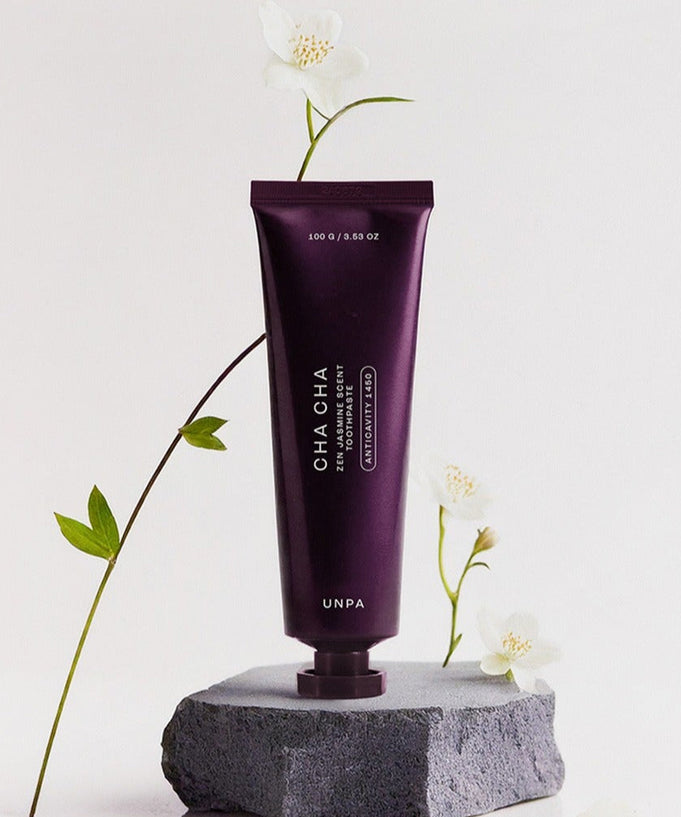 UNPA Cha CHa Zen Jasmine Scent 1450 High Fluoride Toothpaste 100g tube on rock with flowers