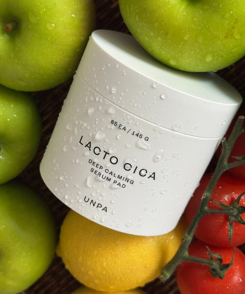 UNPA Lacto Cica Deep Calming Serum Pad 85 Sheets surrounded by fresh fruit for natural elegance.