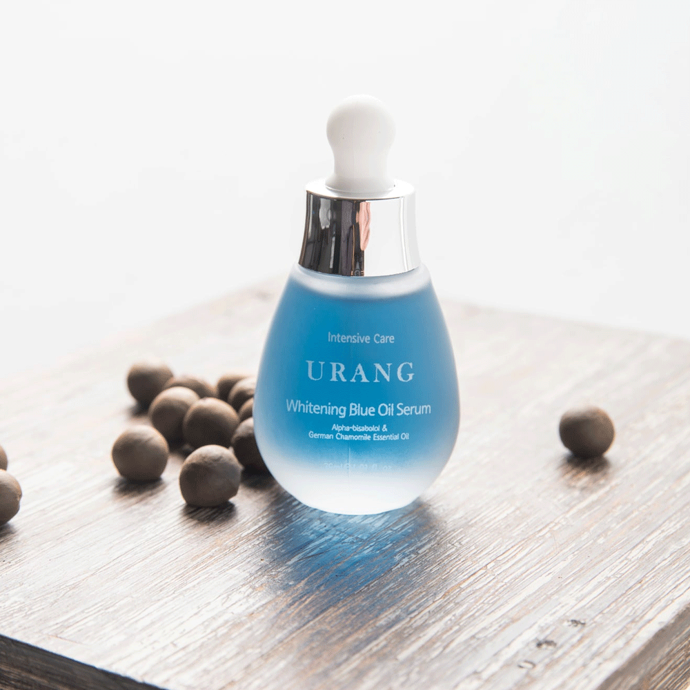 URANG Brightening Blue Oil Serum 30ml on wooden surface with scattered brown nuts