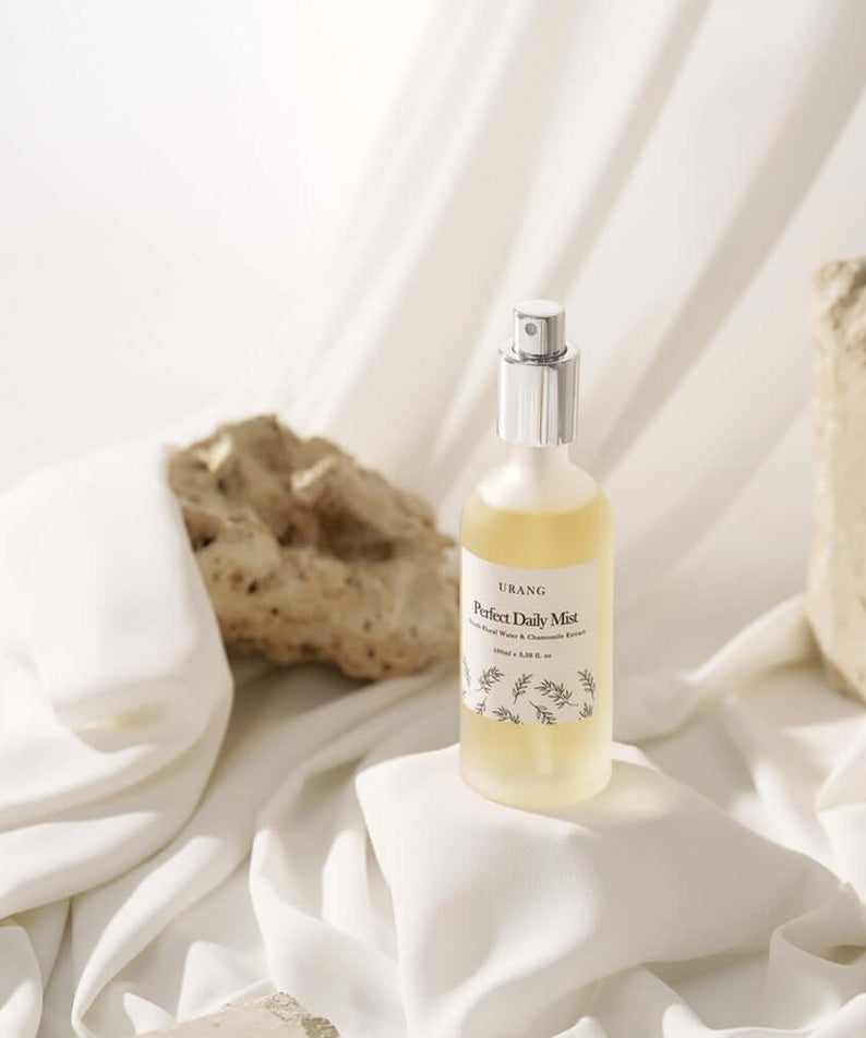 URANG Perfect Daily Mist 100ml bottle on white fabric with rocks in the background
