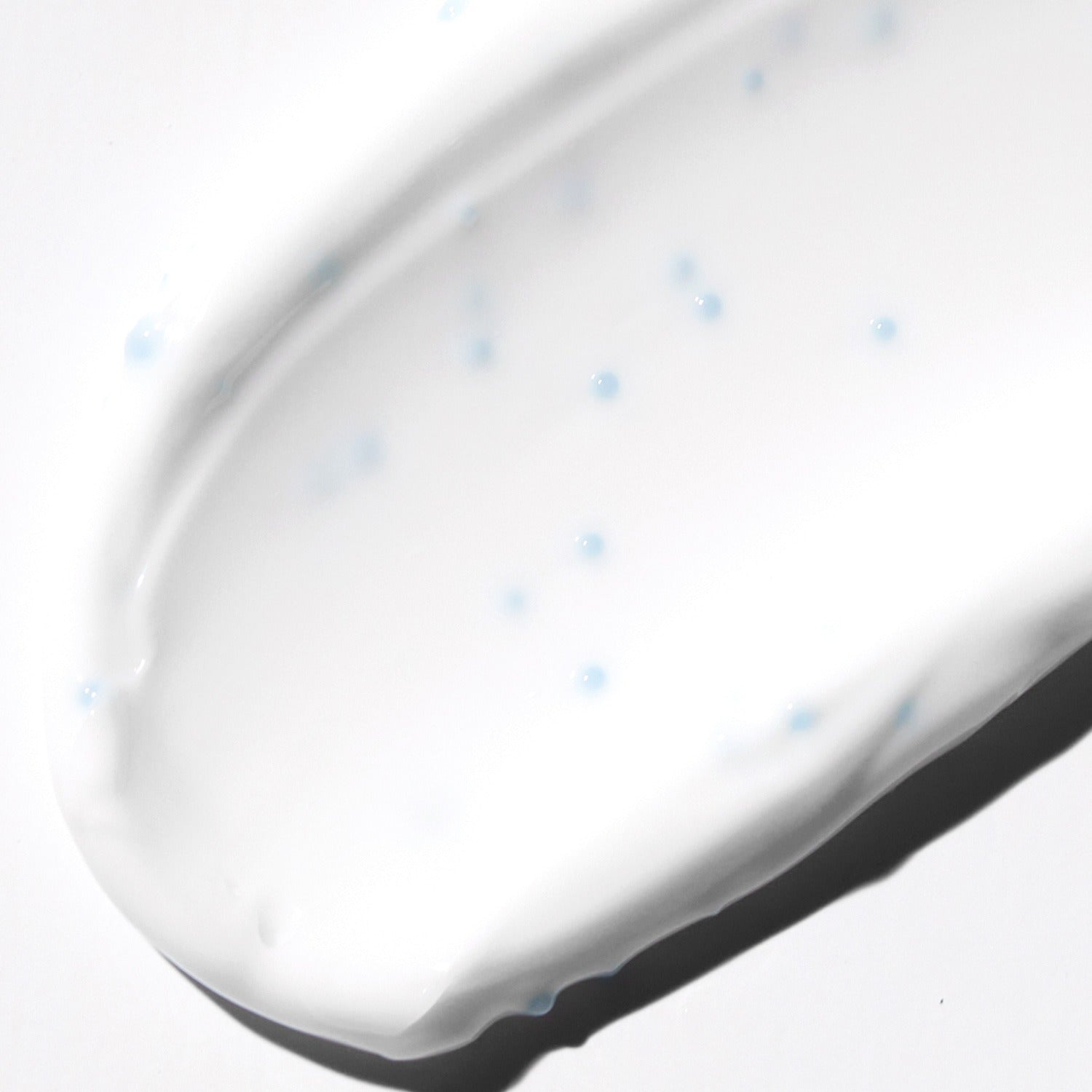 Texture of VT COSMETIC PDRN Cream RX 60ml showing moisturizing cream with blue microbeads on a white background.