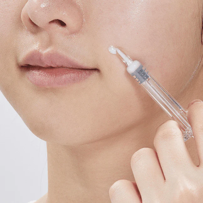 Close-up of woman applying VT COSMETIC Riddle Shot 1300 8ml serum on skin for targeted treatment.
