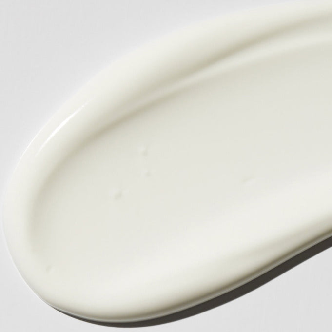 Close-up of VT COSMETIC PDRN Moist Tone-Up Sun Essence 50g's creamy texture on a smooth surface.