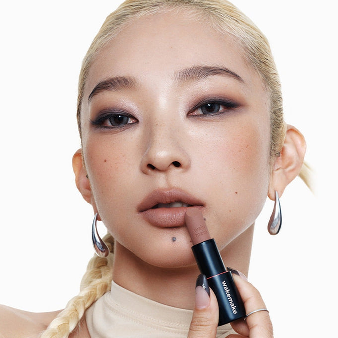 Woman applying WAKEMAKE Soft Blurring Balm Stick to lips for a smooth finish.