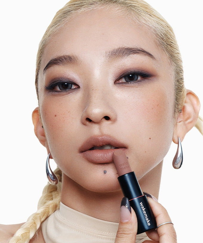 Woman applying WAKEMAKE Soft Blurring Balm Stick to lips for a smooth finish.