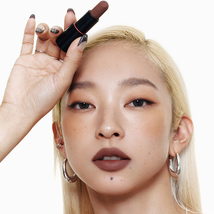 Model holding WAKEMAKE Soft Blurring Balm Stick for a smooth, soft-focus lip finish, emphasizing natural beauty and elegance.