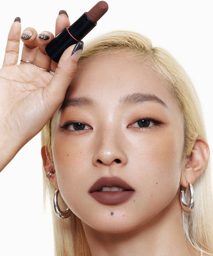 Model holding WAKEMAKE Soft Blurring Balm Stick for a smooth, soft-focus lip finish, emphasizing natural beauty and elegance.