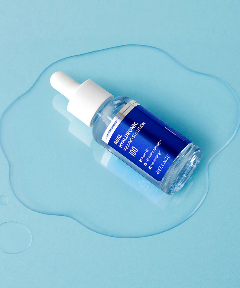 WELLAGE Real Hyaluronic Peeling Solution 30ml serum bottle on a blue background with liquid drops.