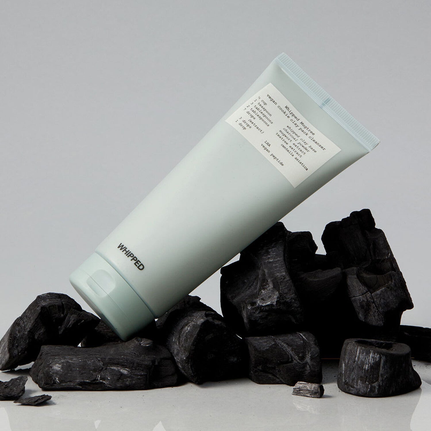WHIPPED Mugtree Vegan Cookie Clay Pack Cleanser 180ml product on display with charcoal background.