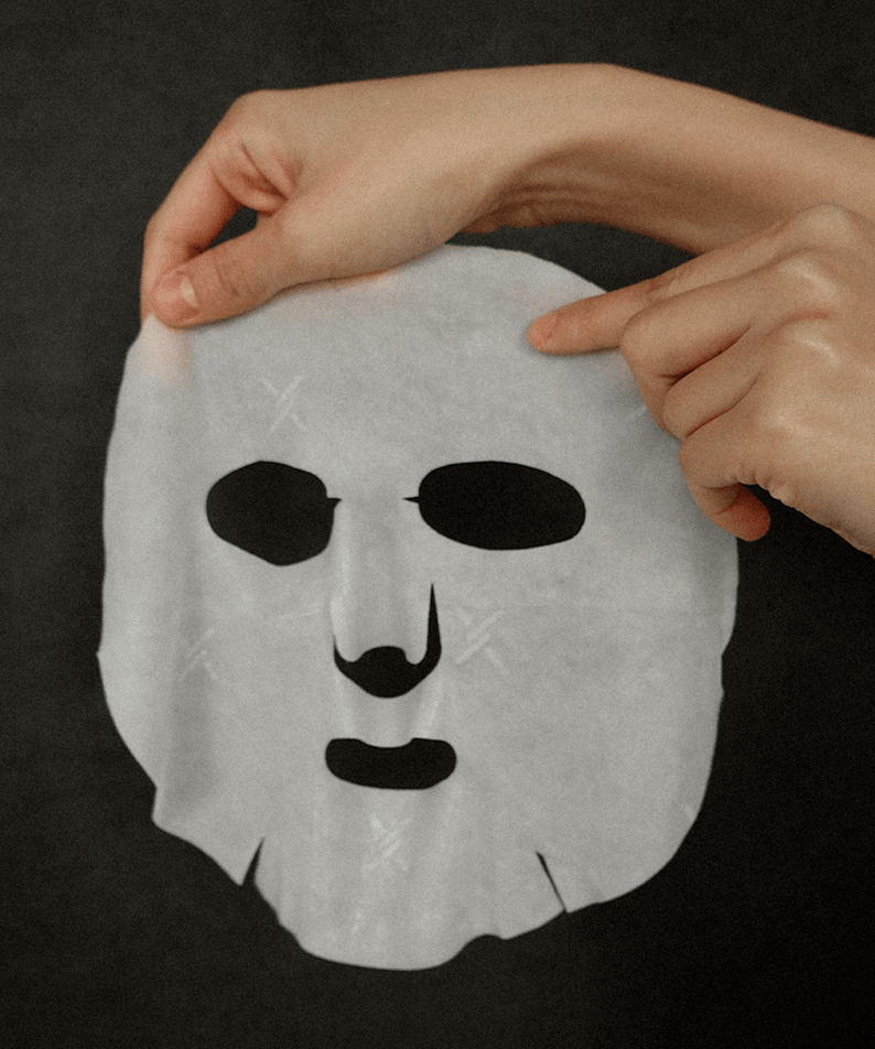 Person holding XOUL Secret Solution Cream Mask 15p against a dark background, showcasing its texture and design.