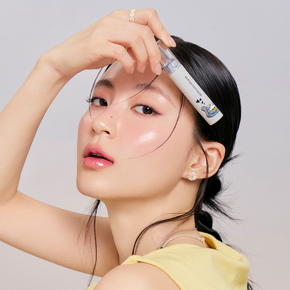 Woman wearing ROMAND x Joanne Friends Glasting Color Gloss showcasing glossy lips with product packaging. Fashion and beauty style.