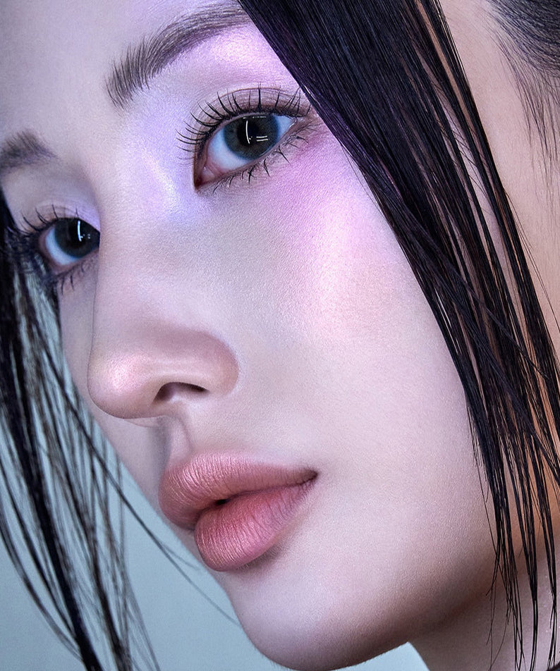 Close-up portrait of a woman with iridescent makeup and sleek black hair