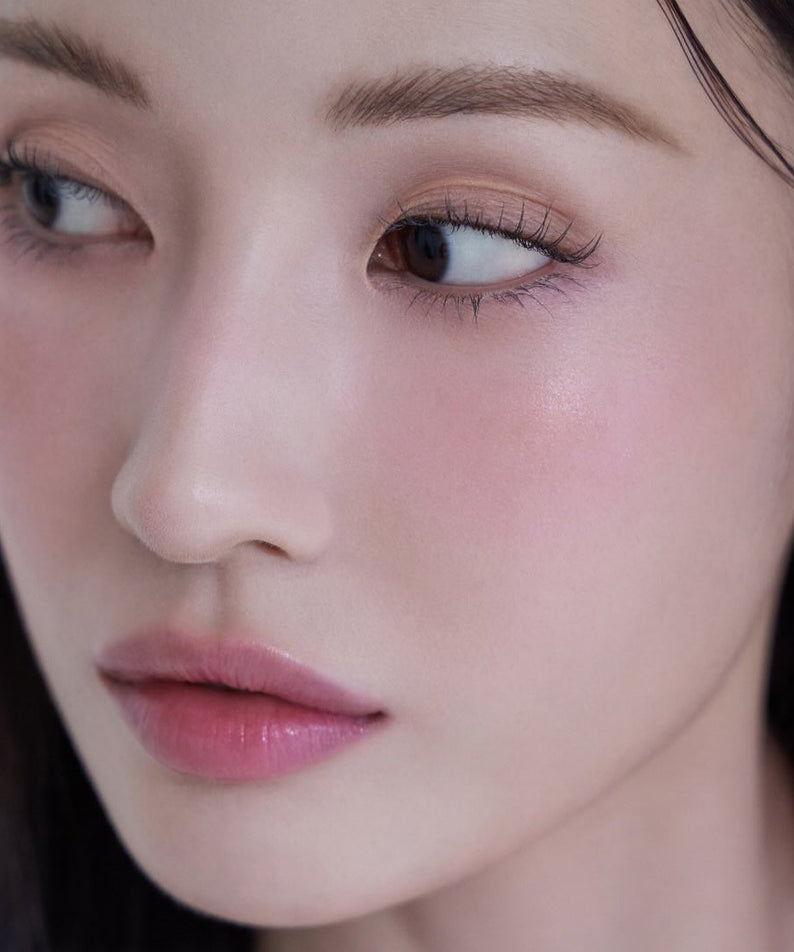 Close-up of a woman's face with natural makeup and subtle glow.