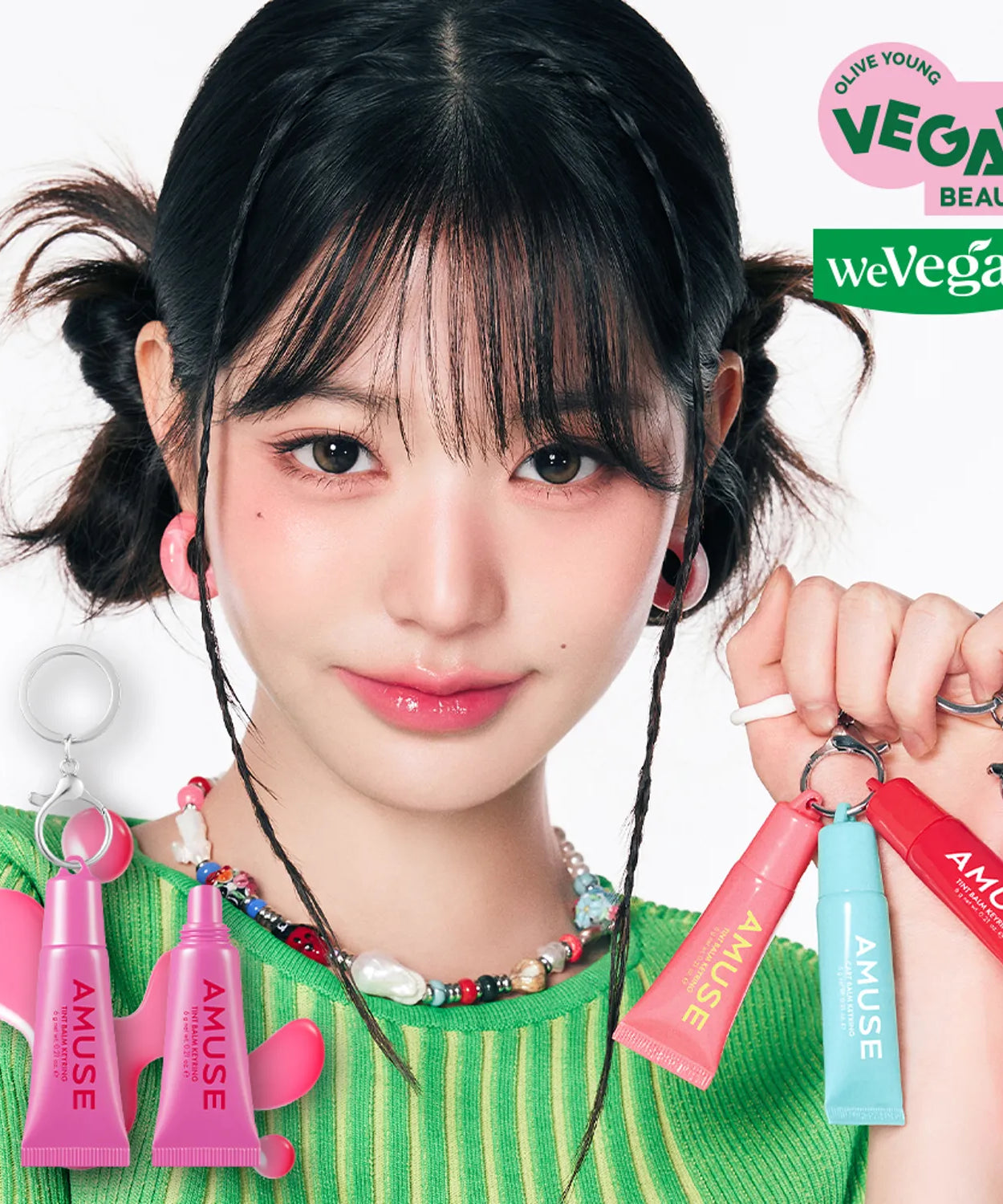 Person holding AMUSE TINT BALM KEYRING with vegan beauty labels in background.