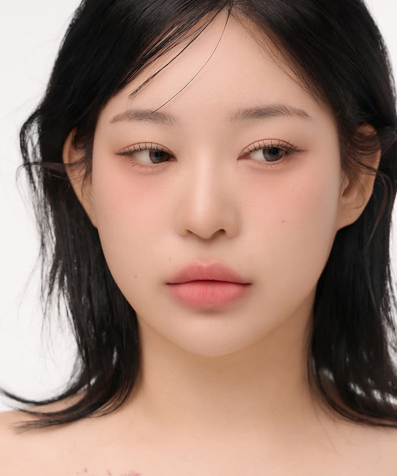 Model wearing natural makeup look with soft pink lips and subtle eye makeup