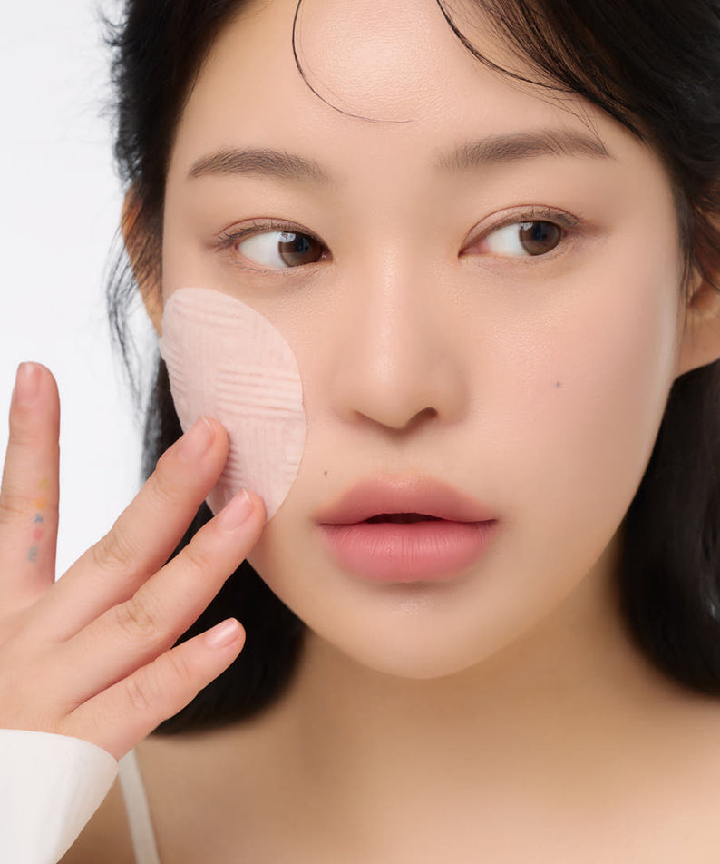 Woman applying AND:AR Centellian in Cica Calming Pads 70 sheets to her face, demonstrating skincare routine