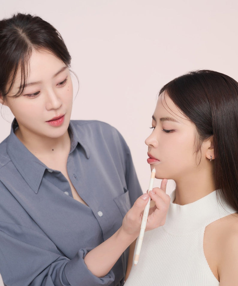 Makeup artist applying AND:AR Soft Skinfit Dual Concealer Pencil on a model's face, showcasing its application and coverage.