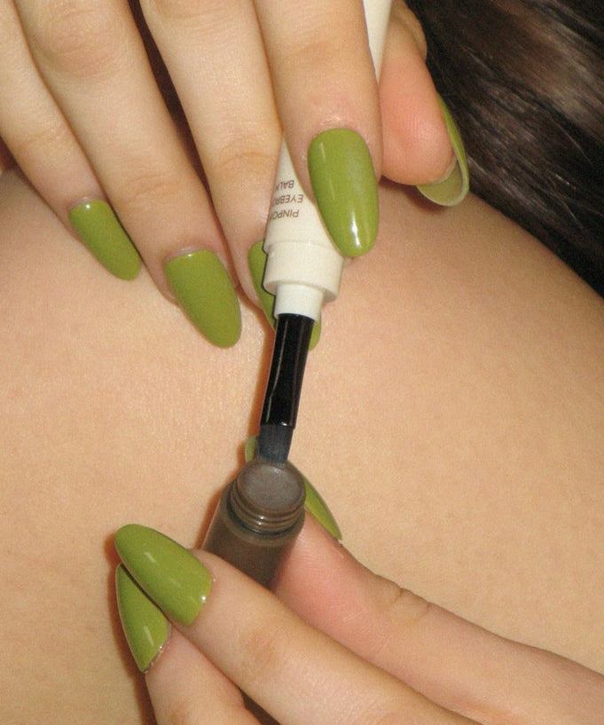 Applying AOU Pinpoint Eyebrow Balm with precision brush for perfect brows