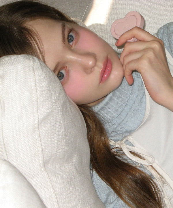 Person holding AOU Soft Cream Blush, showcasing soft pink tones on cheeks, enhancing natural beauty with gentle makeup look.