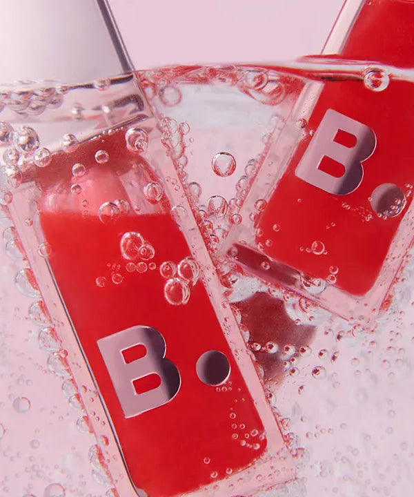 BANILA CO Hydrating Lip Oil bottles in water with bubbles, highlighting the moisturizing formula. Cosmetic beauty product image.