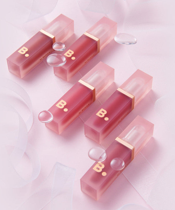 A collection of BANILA CO Water Drop Veil Tint lip tints arranged on a soft pink background, showcasing the product's elegant design.