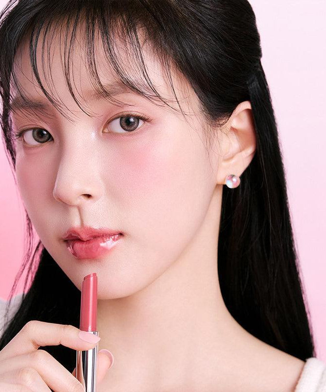 Person applying BBIA Over Glaze Stick on lips with soft pink background