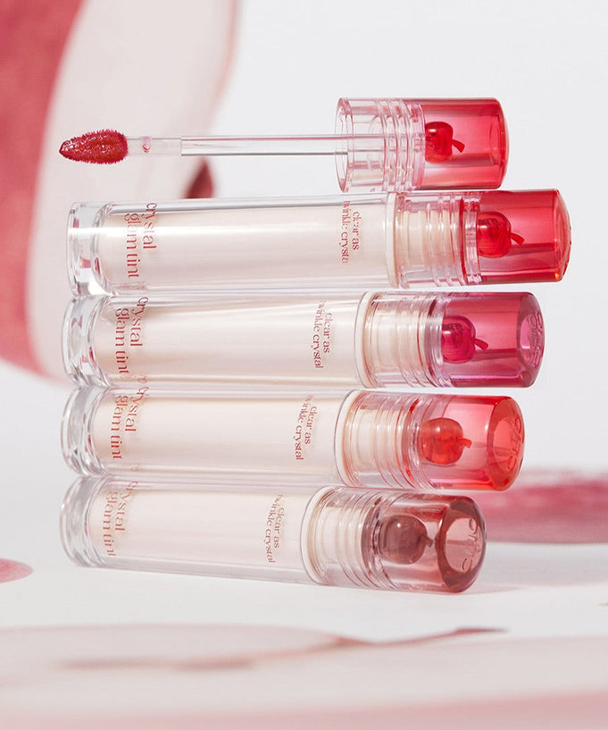 Five tubes of CLIO Crystal Glam Tint lip tint stacked neatly with shades visible, showcasing vibrant makeup colors.