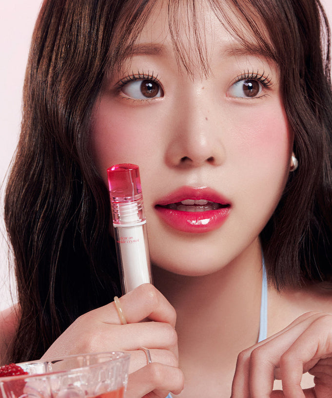 Woman holding CLIO Crystal Glam Tint with glossy lips, showcasing the vibrant effect of the lip product.