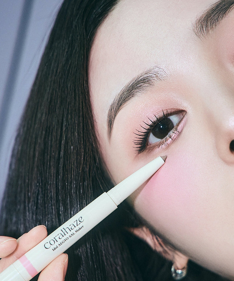 Close-up of a woman using CORALHAZE Idol Aegyo Sal Maker for enhanced under-eye definition.