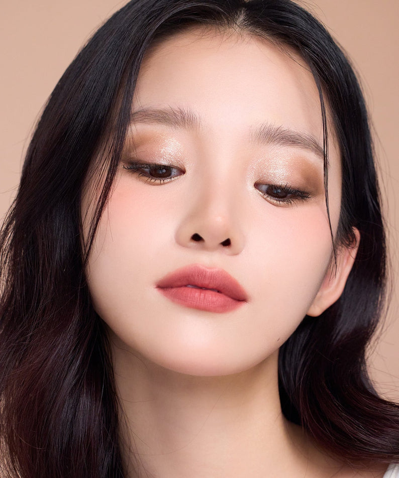 Model wearing DEAR DAHLIA Dream velvet Lip Cloud in warm lighting, showcasing lipstick's smooth texture and rich color on lips.