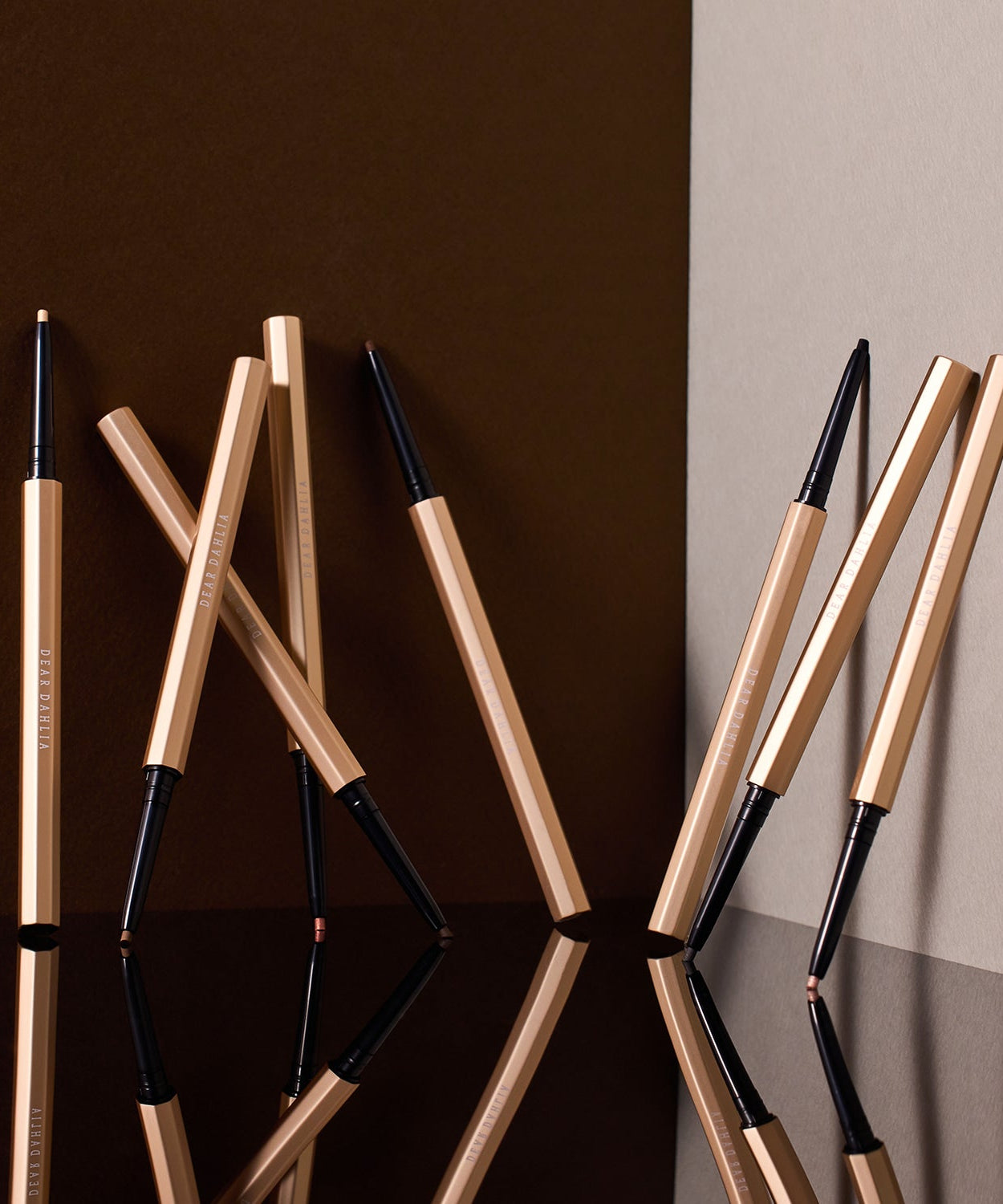 Multiple DEAR DAHLIA Perfect Desighning Eyeliner Pencil displayed artistically on a reflective surface.