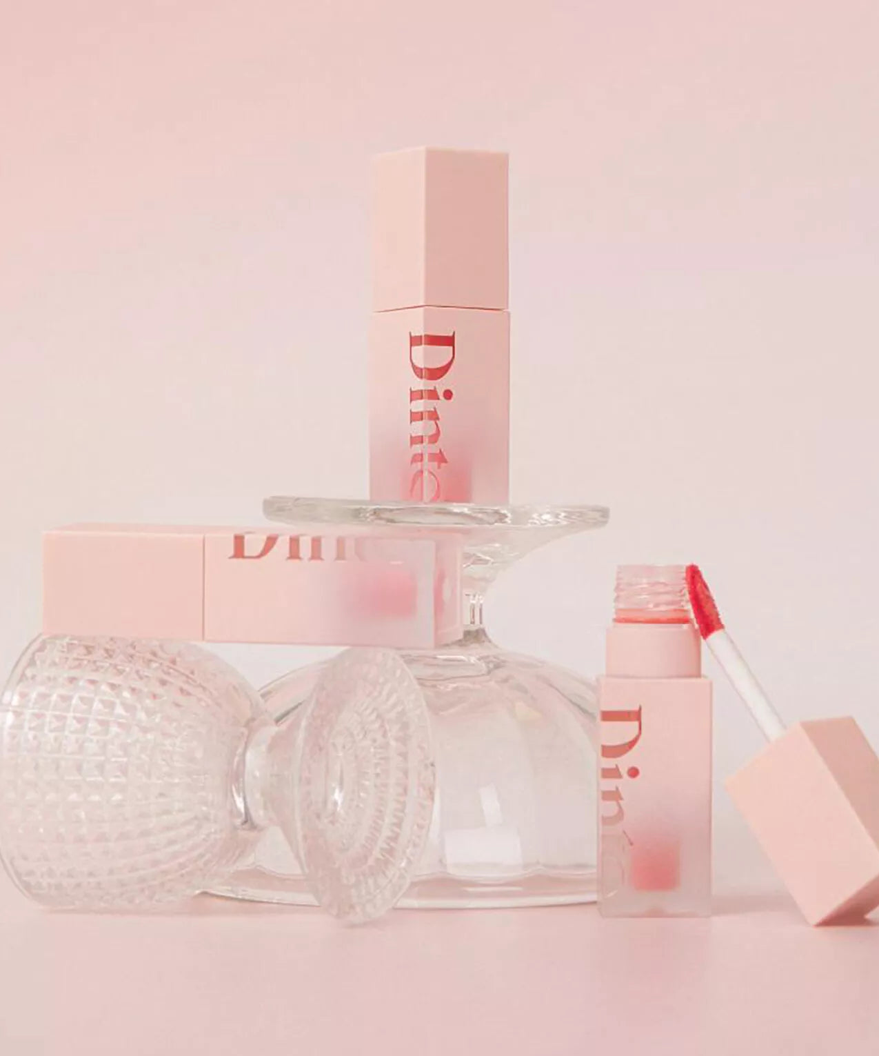DINTO Blur Jelly Plumping Mini Lip Tint in a stylish setup with pink packaging and gloss applicator.